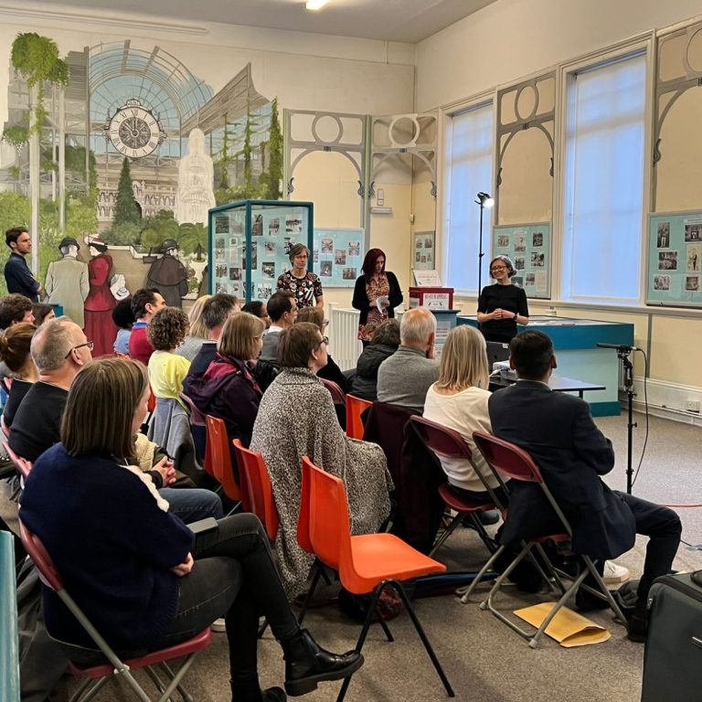 The World on the Upper Terrace talk Side view of audience in room with high ceiling and mural on far wall.facing to the right